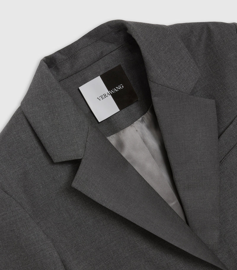 Close-up of a dark gray textured blazer jacket with a visible brand label reading VERWANG on the inner collar, set against a light gray background.