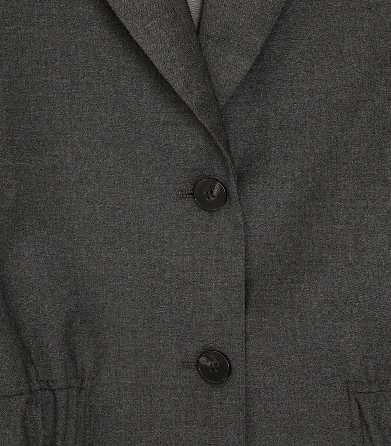 Close-up of a dark gray textured blazer or jacket with two black buttons and a notched lapel.