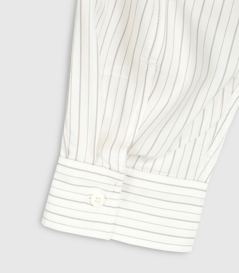 Close-up product view of a shirt sleeve cuff, showcasing the fine ivory and beige pinstripe pattern. The image highlights a structured, square-edged barrel cuff with a single white four-hole button, neat tonal topstitching, and crisp pleat detailing where the fabric gathers into the wrist sleeve placket against a light grey background.
