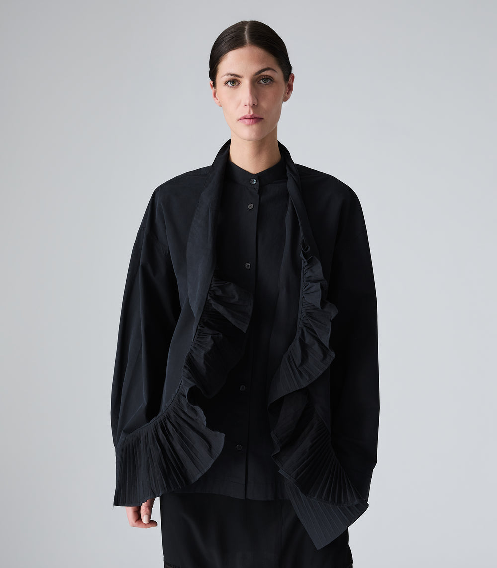 A model wearing a black button-up shirt paired with a black scarf that has a dramatic pleated ruffle trim on both ends, displayed flat against a light gray background.