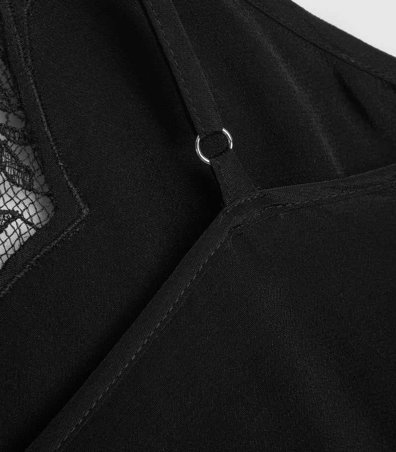 Close-up detail of a black garment showing a shoulder strap with a silver metal O-ring, a seam, and a small portion of black lace mesh.