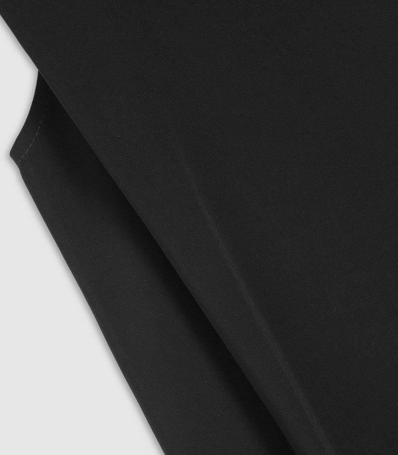 A close-up of a black fabric material with a diagonal fold, showing its smooth texture against a light gray background.