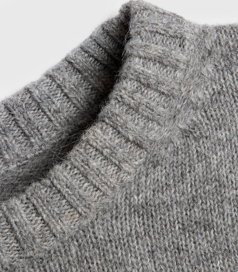 Close-up of a gray ribbed knit sweater showing the texture and collar detail against a light gray background.