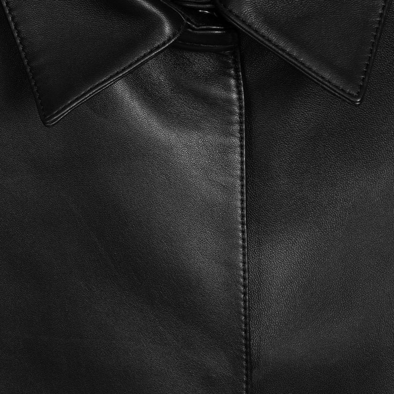 Close-up of a black leather jacket showing the collar, fine grain texture, and precise stitching.