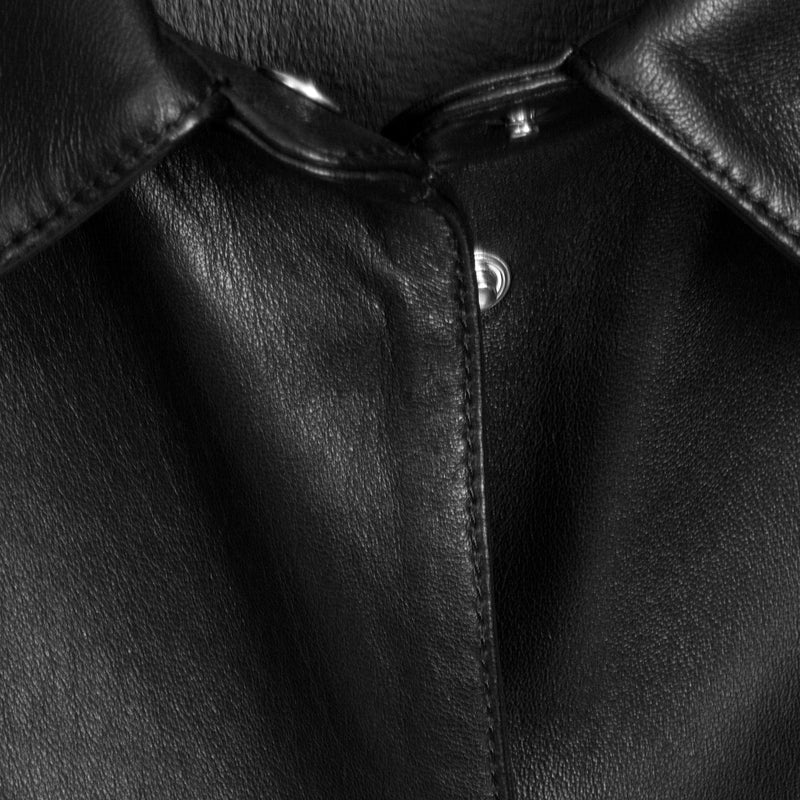 Close-up of a black leather jacket showing the collar, button closure, and fine leather texture.
