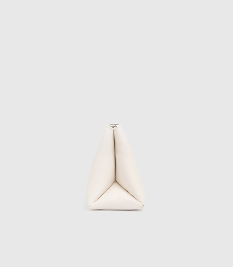 A small, structured triangular clutch bag in off-white leather, centered against a solid light gray background.