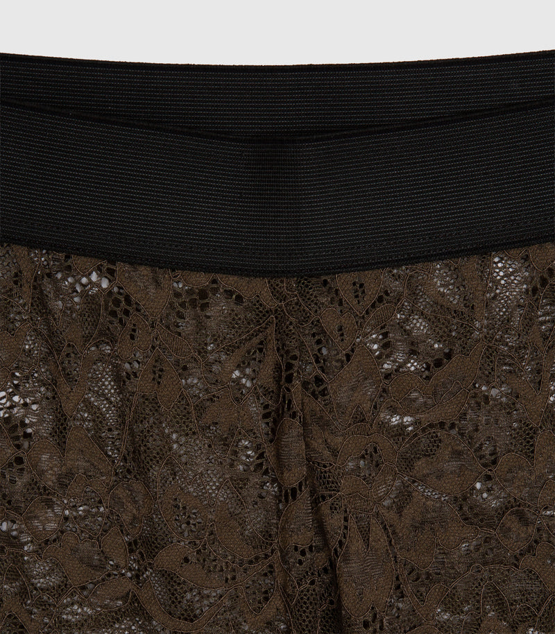 Close-up of a garment featuring a wide black ribbed waistband and dark brown floral lace fabric below.