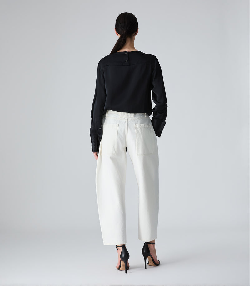 Person wearing a black top and white pants on a plain background