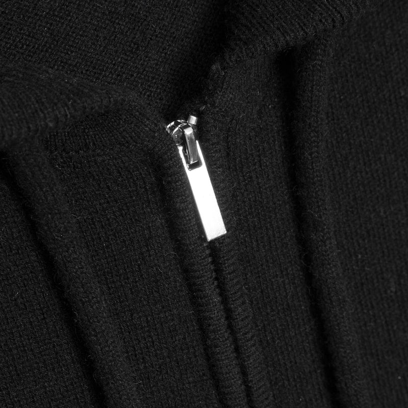 Close-up of a black ribbed knit garment with a silver metal zipper pull.