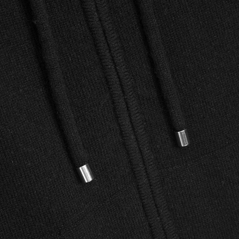 Close-up of a black knit hooded garment showing the drawstring cords and small metallic silver tips.