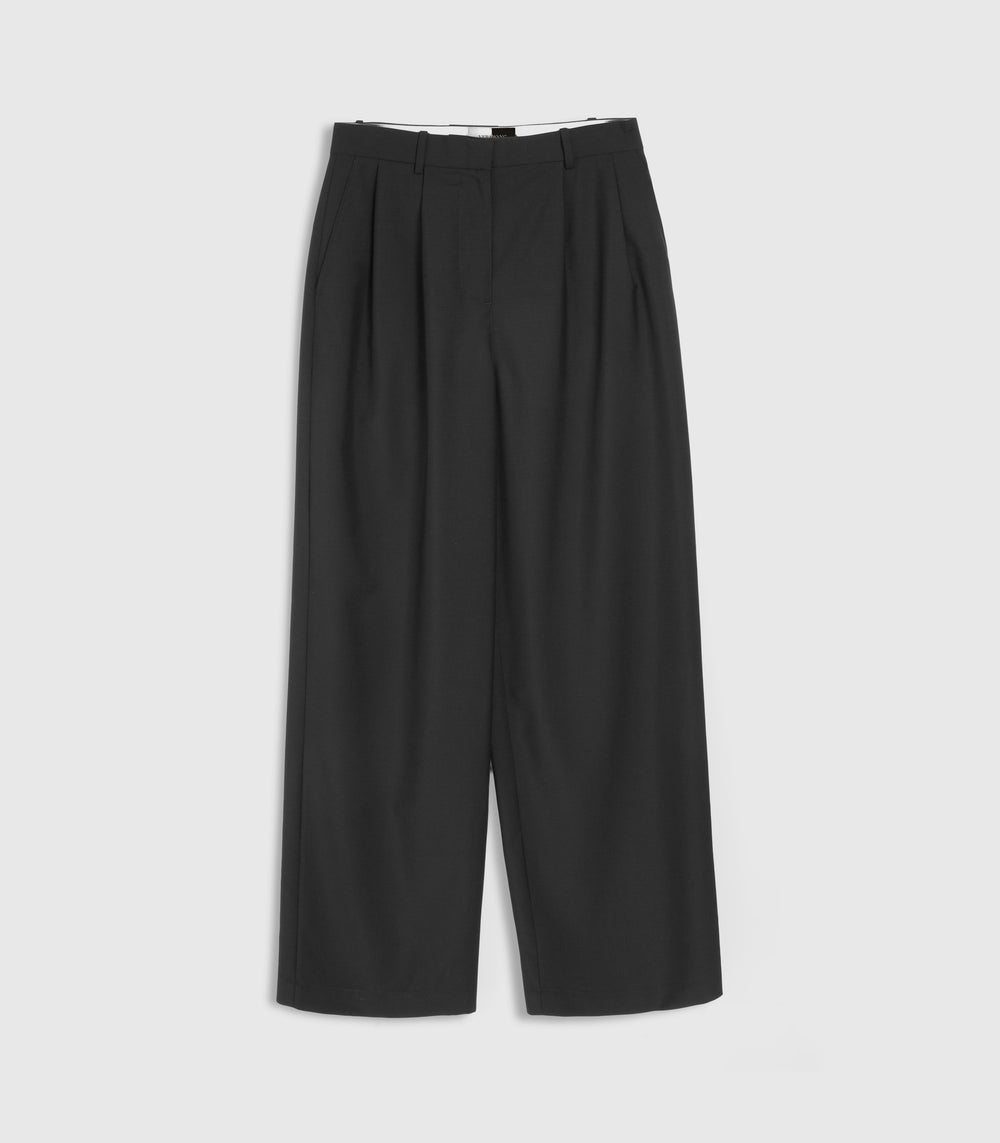 Flat-lay view of high-rise, wide-leg black tailored trousers featuring a relaxed silhouette, structured belt loops, and double front pleat detailing at the waistband. The trousers are designed with a concealed front fly closure and side slip pockets, presented flat against a light grey background.