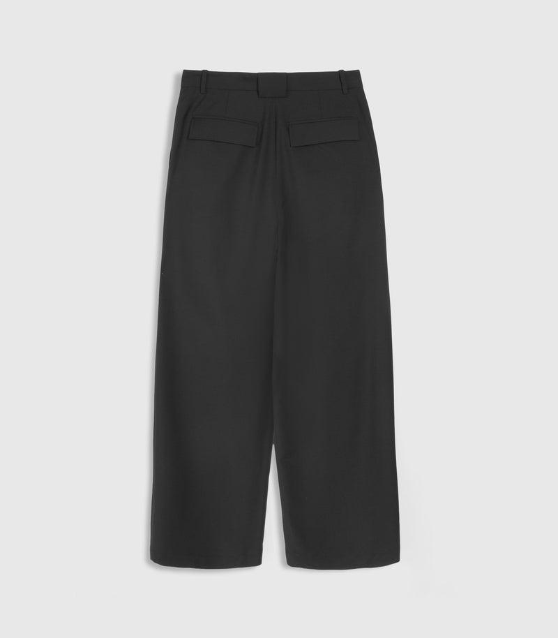 Flat-lay rear view of high-rise, wide-leg black tailored trousers featuring a relaxed silhouette, structured belt loops, and dual horizontal welt pockets with sharp rectangular flaps at the seat. The trousers are constructed with a clean central back seam and vertical darts for a tailored fit, presented against a light grey background.