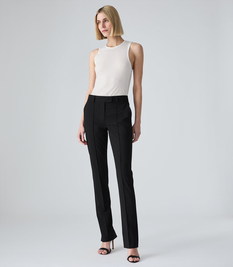 Woman wearing a white blouse and black pants on a white background