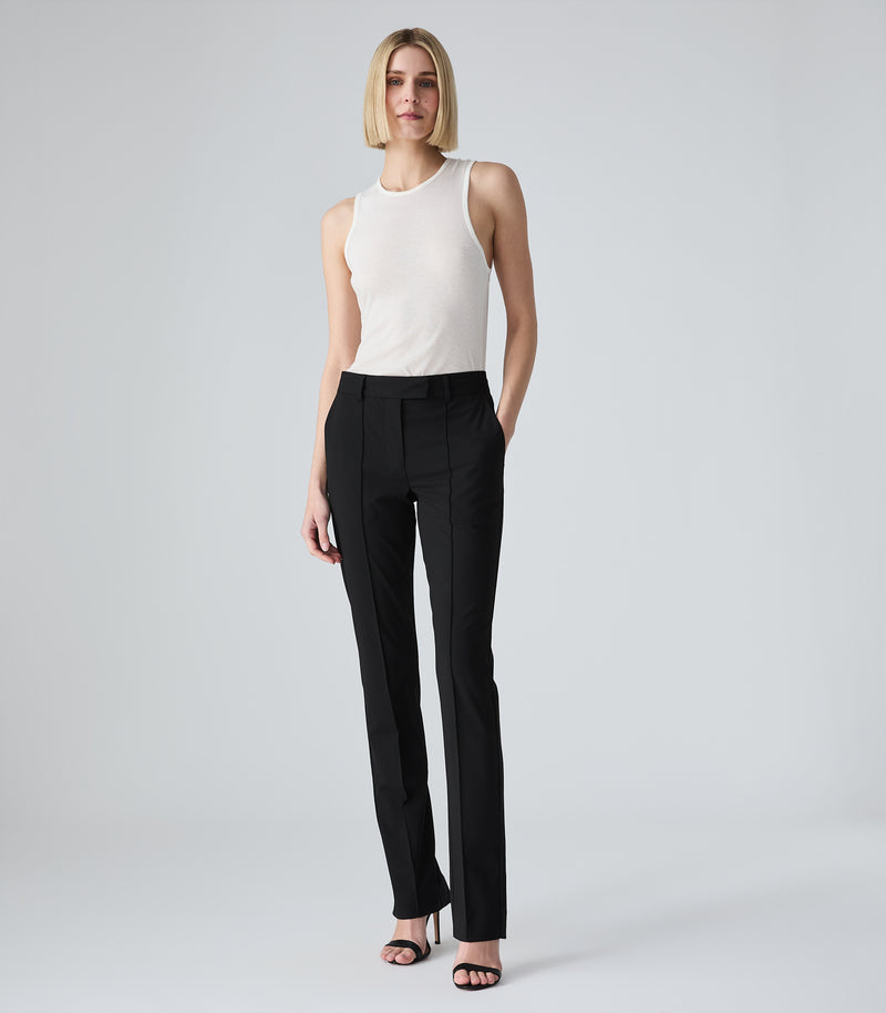 Woman wearing a white blouse and green pants on a white background