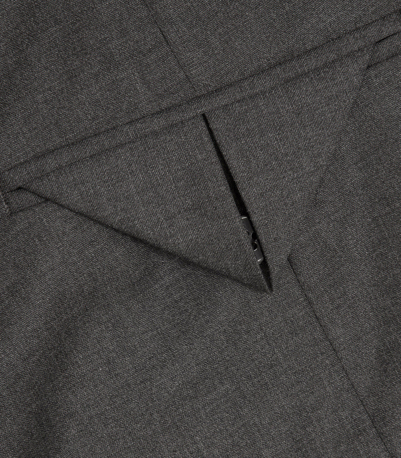 Close-up of dark gray textured fabric with a diagonal seam and a small metal rivet detail.