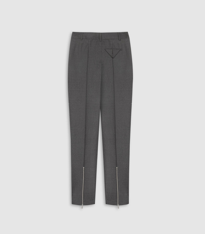 A pair of dark gray tailored trousers with a subtle micro-pattern, featuring a pointed V-shaped decorative detail on the front of the right leg and silver-toned zipper accents running down the front of each leg.