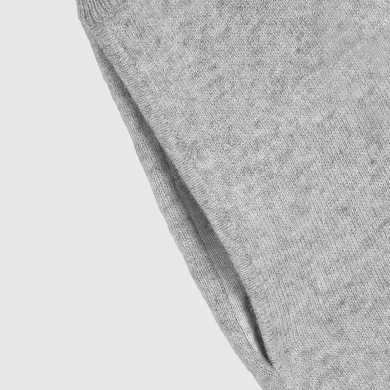 Close-up of a light gray heather knit fabric, showing the texture and ribbed edge against a white background.
