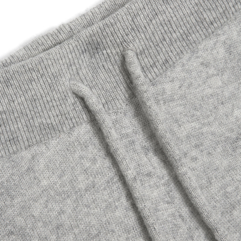 Close-up of a light gray heather knit fabric with a ribbed waistband and drawstring detail.