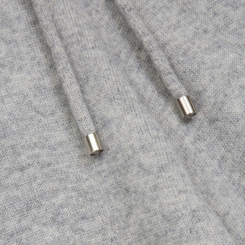 Close-up of a light gray heather knit fabric with two metallic silver drawstring tips visible.