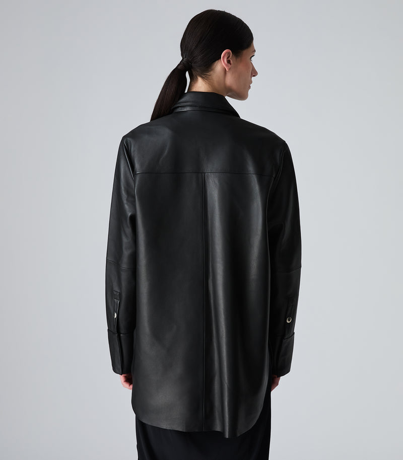 A model shown from the back wearing a black leather shirt jacket against a light gray studio background.