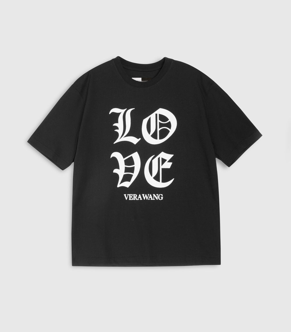 Flat lay product view of a loose-fit black t-shirt featuring 'LOVE' printed in large white Old English gothic lettering with the 'VERA WANG' brand logo directly underneath, complete with a classic crew neckline and short sleeves against a light grey background.