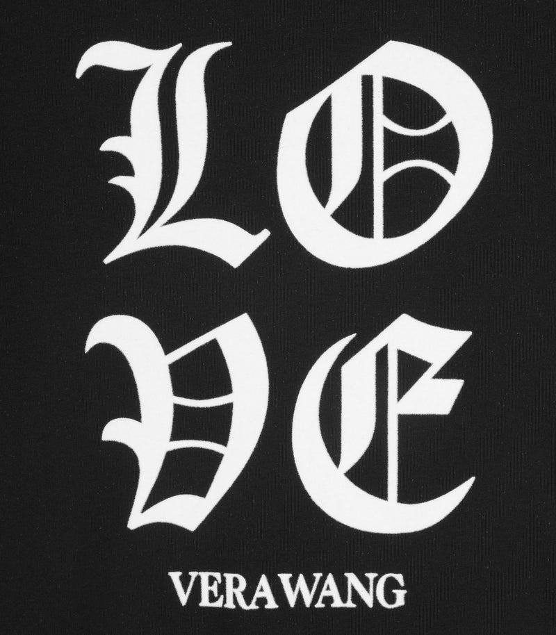 A close-up product shot focusing on the chest graphic of a black cotton t-shirt, showcasing the crisp white printed 'LOVE' text in a bold Old English gothic font with the 'VERA WANG' brand logo printed directly underneath.