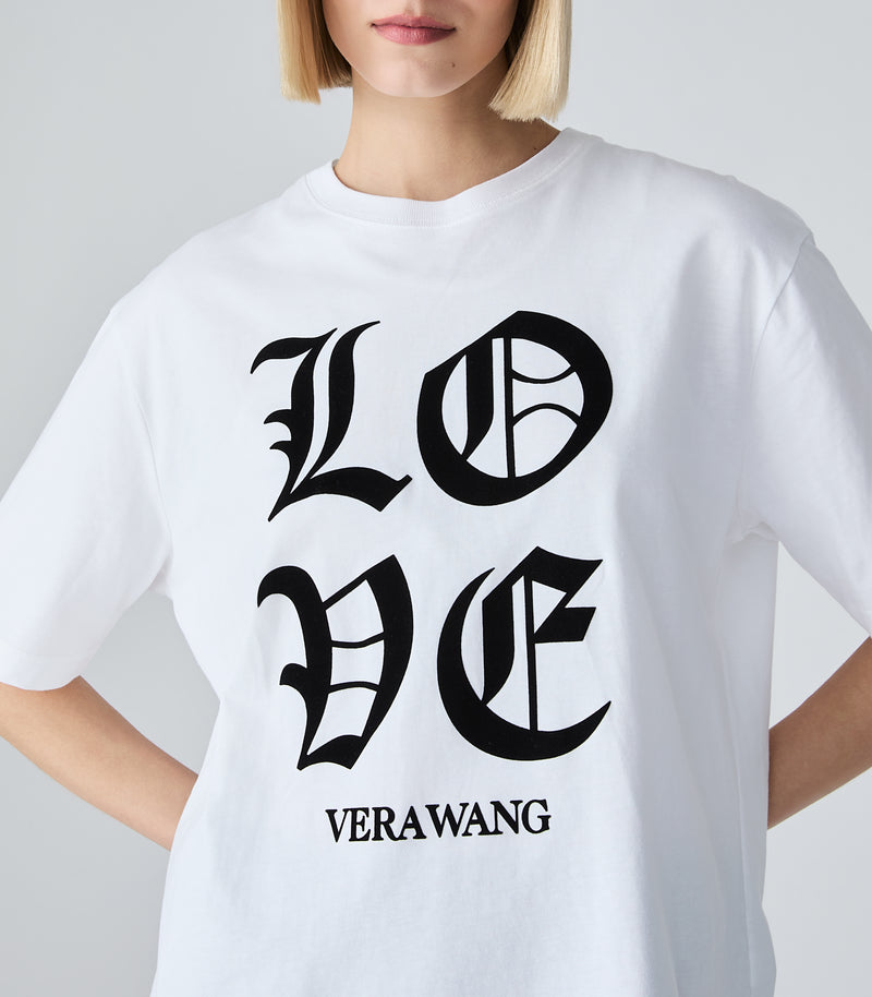 A closer shot of a person wearing a white t-shirt with a black 'LOVE VERA WANG' spell-out logo across the front, against a white background.
