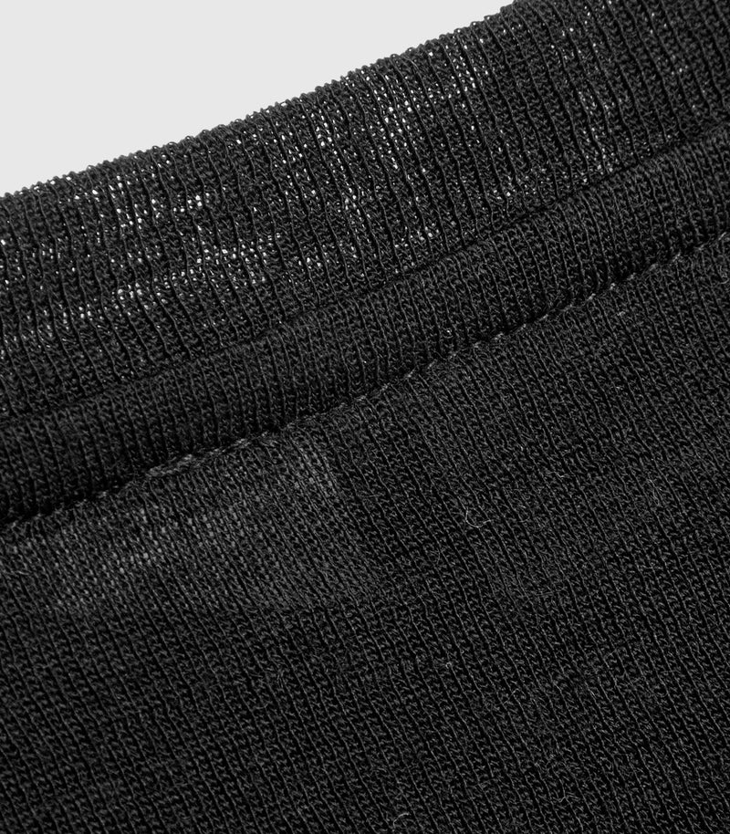Close-up of a black ribbed knit fabric, showing the texture and stitching detail against a light gray background.