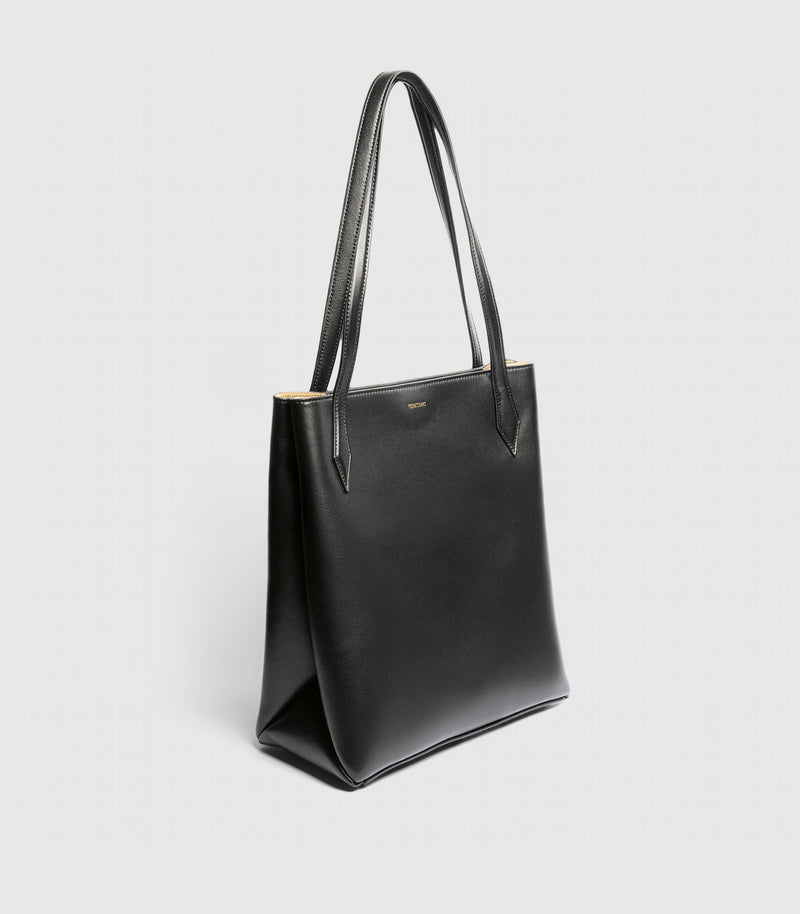 A black leather tote bag with double shoulder straps, shown from a three-quarter angle against a light gray background.
