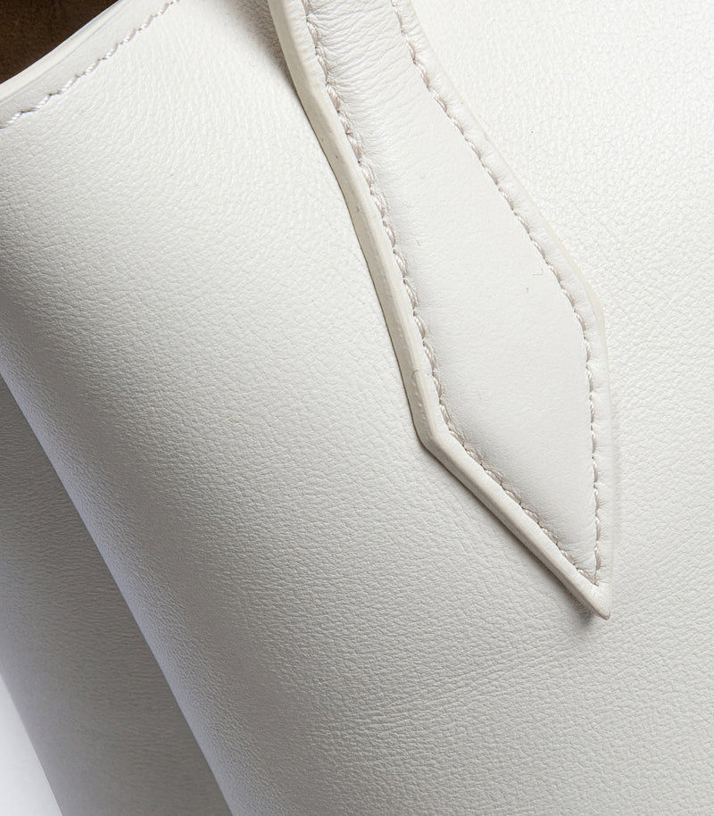 Close-up of a white textured leather boot or shoe showing a pointed stitched detail on the side.