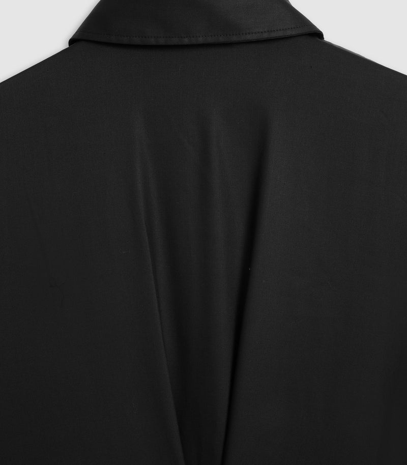 Close-up of a black collared garment, showing the back of a black jacket or coat with a smooth matte fabric texture.