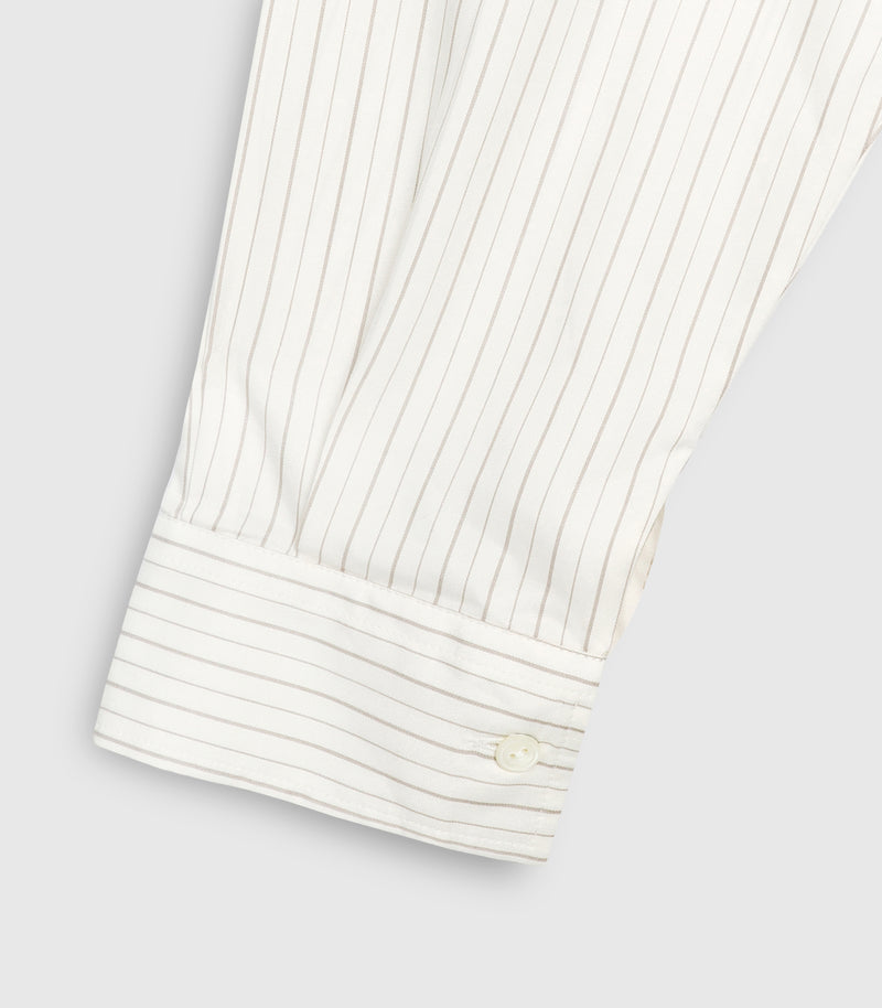 Close-up product view of a shirt dress sleeve cuff, showcasing the delicate ivory and beige pinstripe pattern. The image highlights a structured buttoned cuff featuring a single tonal four-hole button, precise topstitching along the border, and fine fabric pleats where the sleeve material gathers into the wrist placket, set against a light grey background.