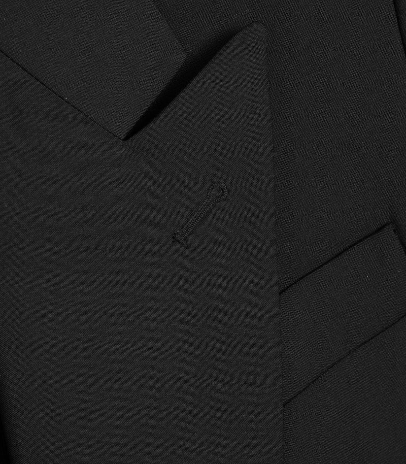 Close-up of a black suit jacket with a brand logo on a black background
