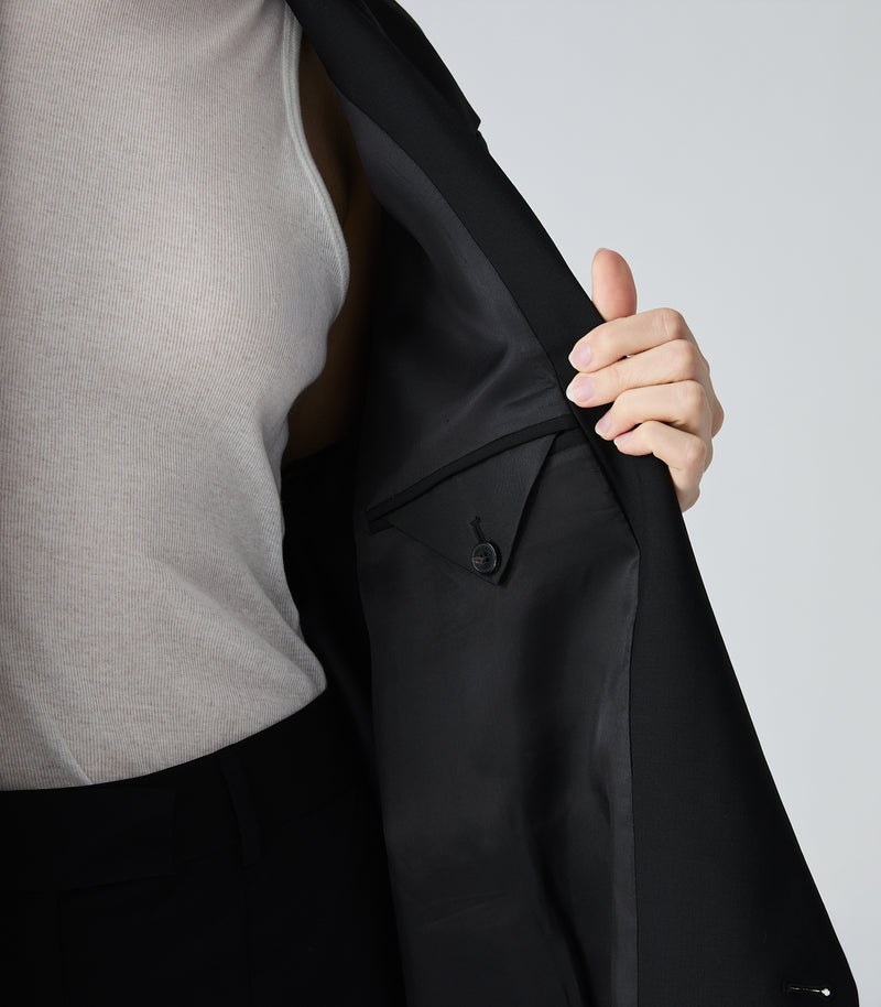 Displays a model wearing the Black 'Vera Wang' branded Miles F35 Stretch Wool Blazer featuring a close up of inside the jacket 