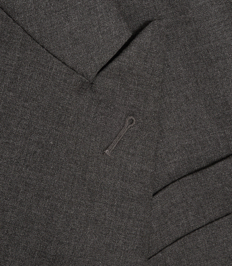 Close-up of dark charcoal gray textured fabric with a small matching dark button and subtle stitched detail.