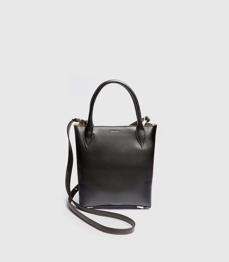 Black handbag with a shoulder strap on a light gray background