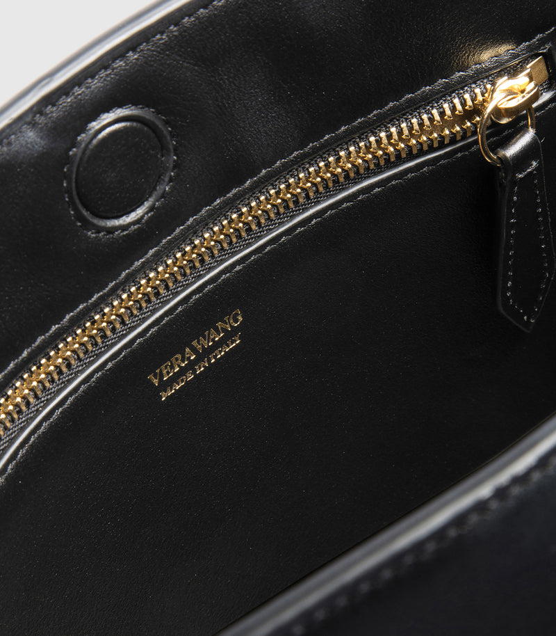 Black handbag with gold zipper and 'VERA WANG' branding.