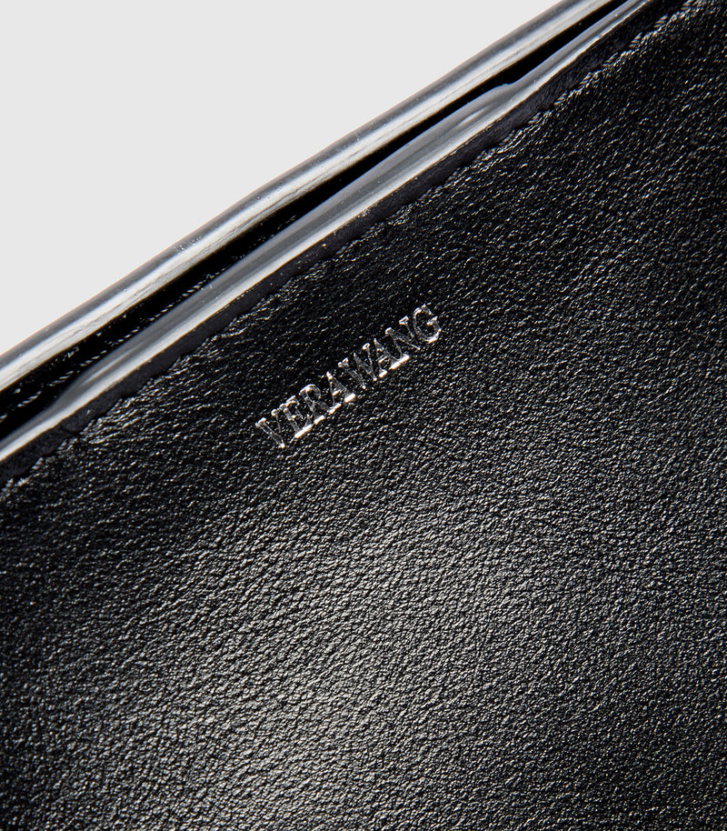 Close-up of a black leather product with 'VERA WANG' branding.