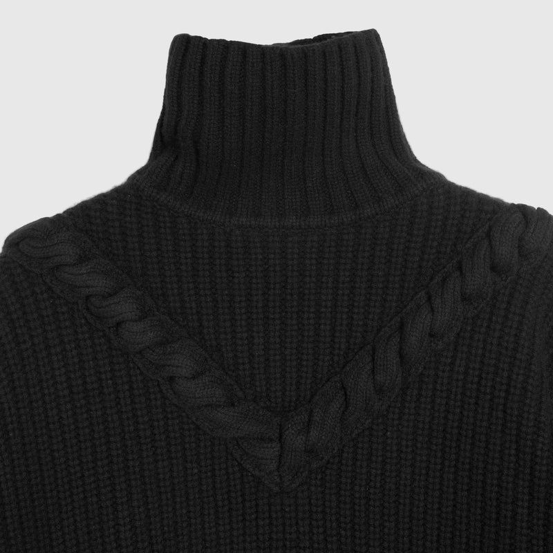 Close-up of a black ribbed knit turtleneck sweater with a braided V-neck detail, shown against a plain white background.