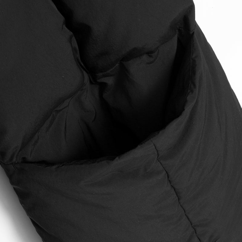 Close-up of a black puffer jacket showing the quilted fabric texture and stitched paneling against a white background.