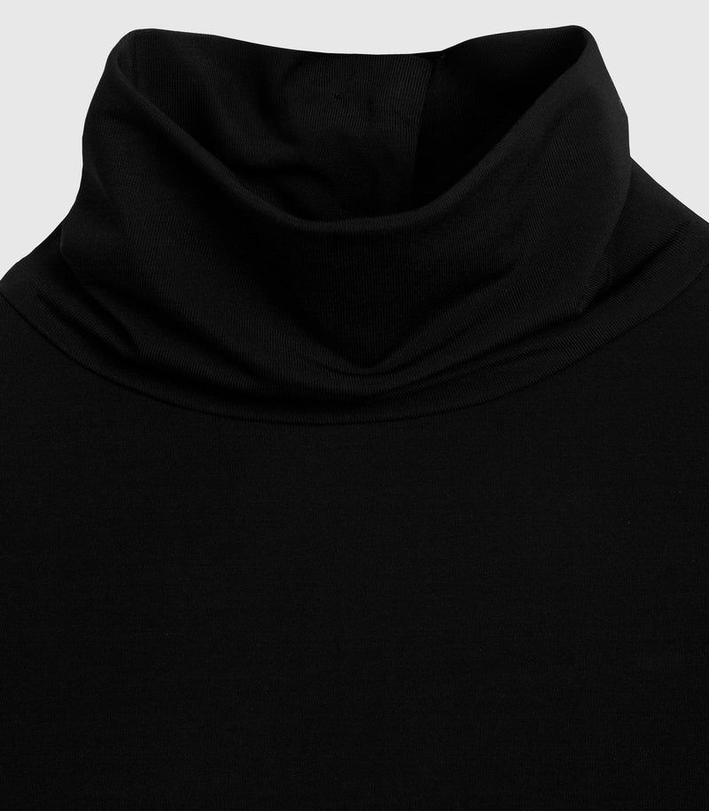 A macro close-up product view focusing on the high neckline construction of a matte black maxi dress. The image highlights the soft, fluid folds of a double-layered funnel neck or soft roll-neck collar. It showcases the fine, smooth texture of the premium jersey-style knit fabric and the flawless stitching where the collar seamlessly integrates into the shoulder panel, set against a light grey background.