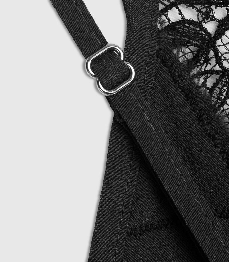 Close-up detail of a black lace and mesh lingerie top showing a silver metal adjustment ring on a strap against a light gray background.