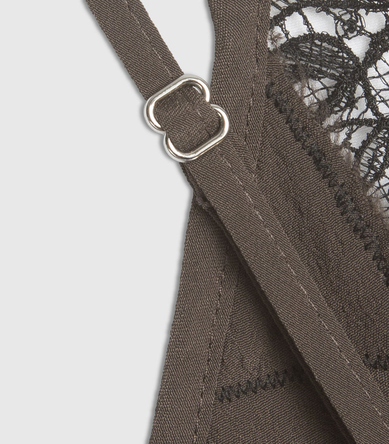 Close-up detail of a dark brown dress strap with silver metal rings and a black lace edge visible on the left.