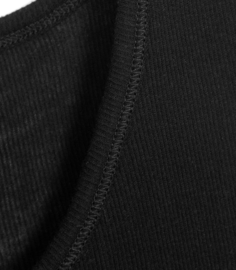 Macro close-up product view of a black tank top, showcasing the curved edge of the neckline binding with meticulous tonal coverstitching. The image highlights the premium, ultra-fine vertical ribbed knit textile structure and clean garment construction details.