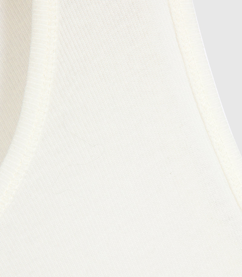 Macro close-up view of an ivory tank top, highlighting its soft, fine-gauge vertical ribbed-knit texture. The shot focuses on the clean, reinforced topstitching running along the narrow ribbed binding of the neckline and armhole borders.