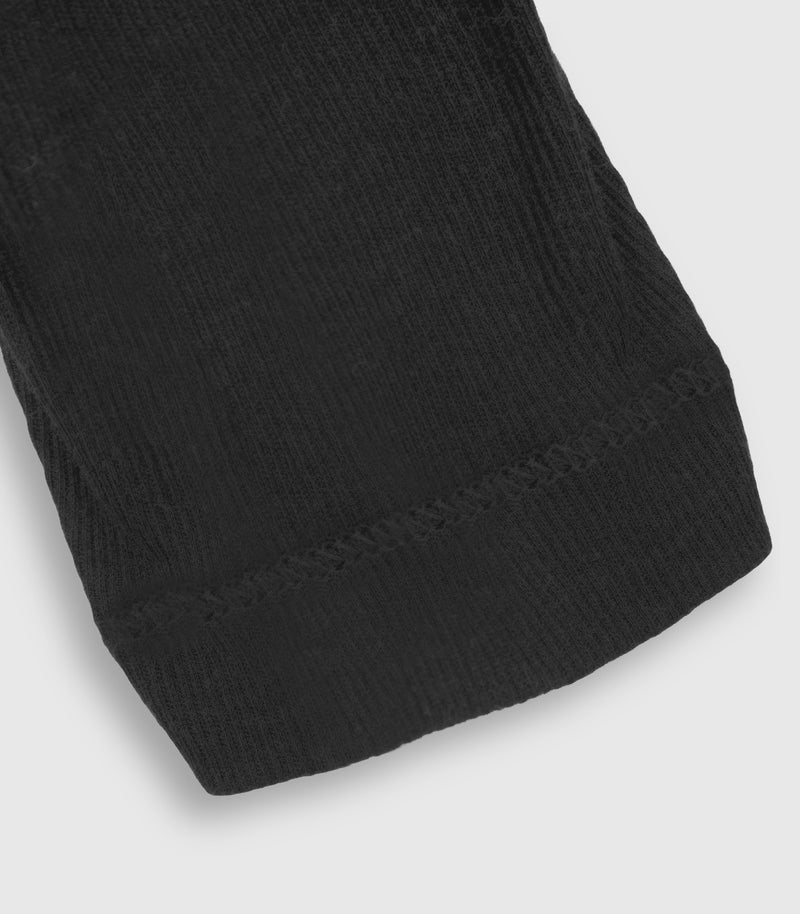 Close-up of a black ribbed knit fabric sleeve cuff, showing the ribbed texture and hem stitching on a light gray background.
