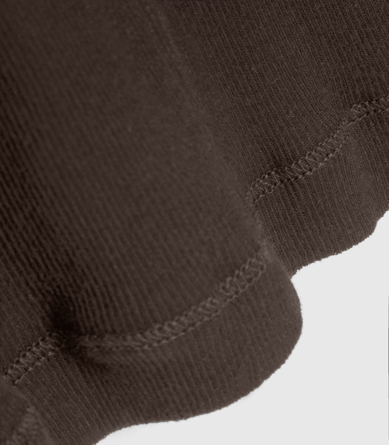 Close-up of a dark brown ribbed knit fabric with stitched hem detail against a light gray background.