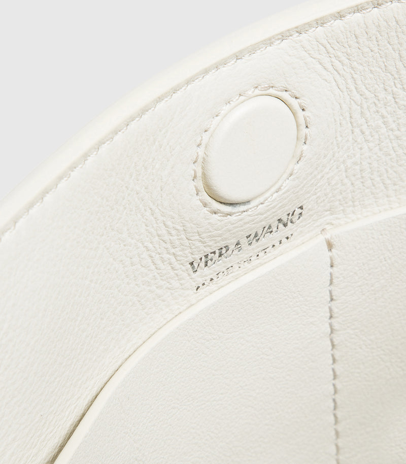Close-up of a white leather handbag with 'Vera Wang' branding.