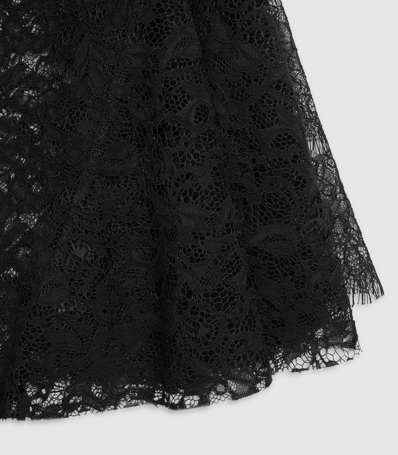 Close-up of a black lace fabric with an intricate floral pattern and sheer tulle overlay, shown against a light gray background.