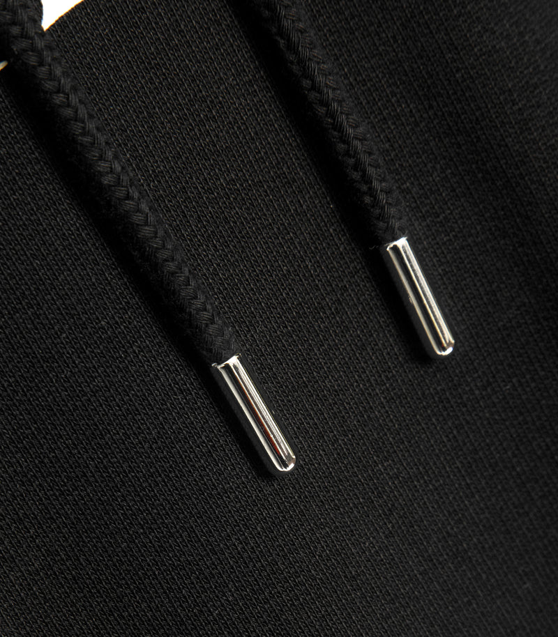 A close-up shot of the silver metal aglets on the hoods drawstrings.